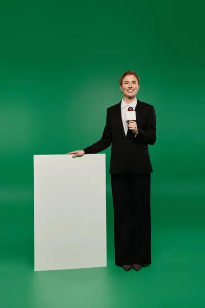 The TV presenter showcases professionalism in black attire, poised beside a blank canvas, ready to engage viewers. — Stock Photo
