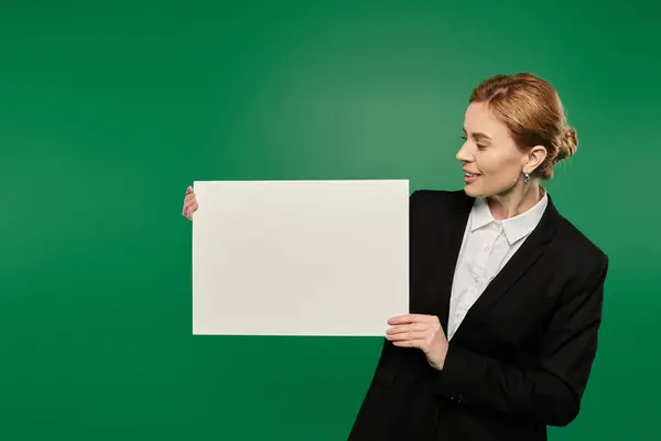 A charismatic presenter in black engages viewers with a blank board before a green backdrop. — Stock Photo