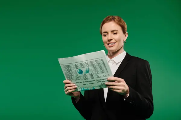 A poised TV presenter in elegant black attire reads a news, radiating confidence against a green backdrop. — Stock Photo