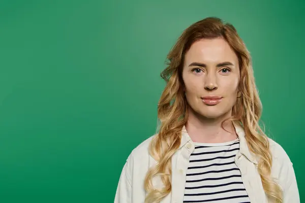 A woman with lovely curly hair stands confidently against a vibrant green background, exuding casual charm. — Stock Photo