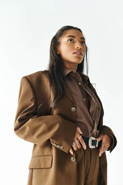 A young woman showcases her fashion sense in elegant brown attire while striking a confident pose. — Stock Photo