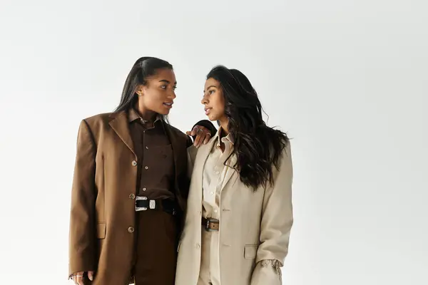 Two stylish young women chat animatedly, radiating confidence and fashion. — Stock Photo