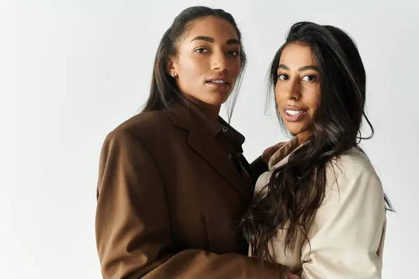 Charming young women embrace in a stylish indoor setting, radiating confidence and fashion. — Stock Photo