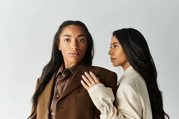 Dos mujeres jóvenes, vestidas con trajes de moda, muestran su estilo único y su estrecho vínculo. - foto de stock