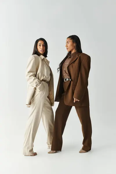 Two young women display fashionable outfits, radiating confidence and style in a bright studio. — Stock Photo