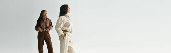 Two young women exude confidence in chic outfits, surrounded by a serene, minimalist setting. — Stock Photo