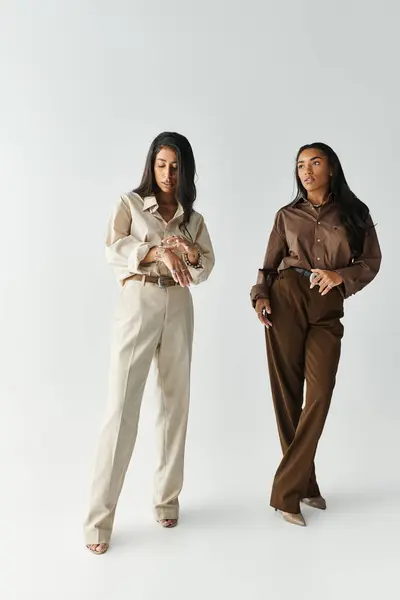 Two fashionable young women display their stylish outfits with confidence in a bright space. — Stock Photo