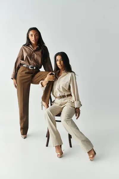 Two young women in fashionable outfits pose confidently against a neutral background. — Stock Photo