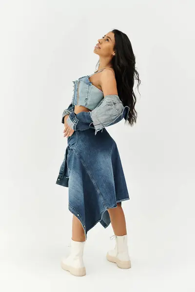 A fashionable young woman dressed in chic denim looks up thoughtfully, radiating elegance and poise. — Stock Photo