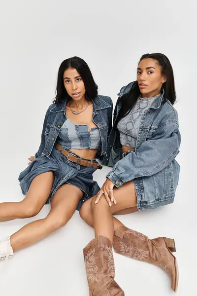 Deux jeunes femmes posent élégamment dans des ensembles de denim à la mode, rayonnant de confiance et de style. — Photo de stock
