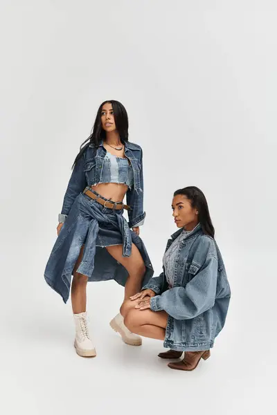 Due donne alla moda mostrano con sicurezza il loro elegante abbigliamento in denim, irradiando energia giovanile. — Foto stock