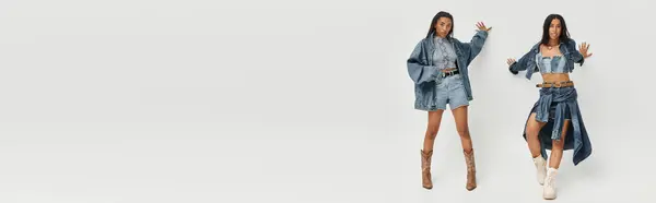 A young woman in fashionable denim explores her stylish outfit in a well lit studio space. — Stock Photo