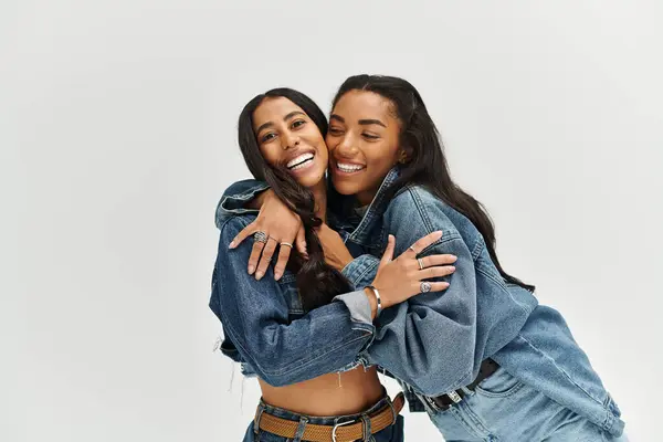 Two young women celebrate friendship while wearing fashionable denim attire with playful energy. — Stock Photo