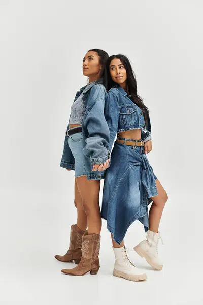 Two stylish young women in trendy denim jackets pose confidently against a plain background. — Stock Photo