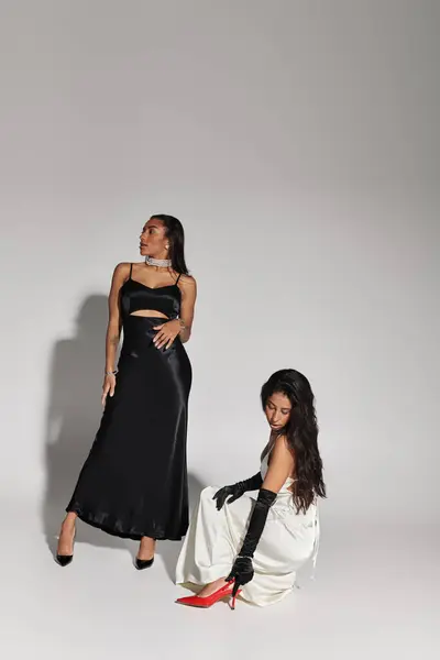 Two young women, dressed in chic attire, strike elegant poses against a minimalist backdrop. — Stock Photo