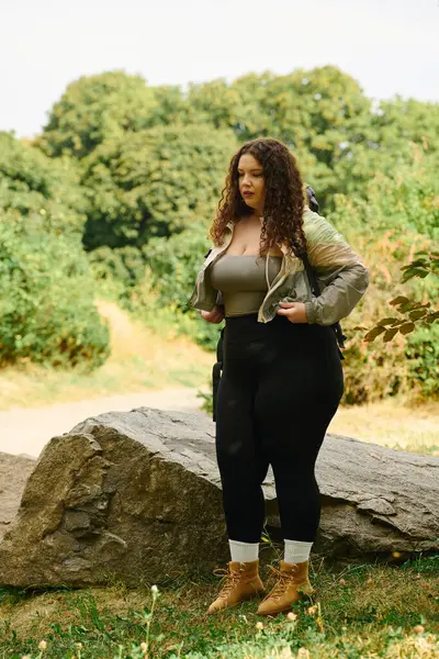 Una mujer alegre abraza la naturaleza mientras está parada en medio de una exuberante vegetación, irradiando confianza y belleza. - foto de stock