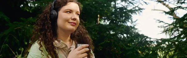 The plus size woman savors a tranquil moment in a lush green forest, lost in music and thought. — Stock Photo
