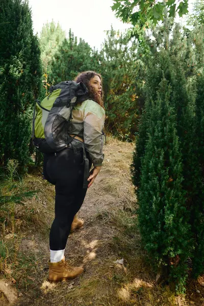 A joyful plus size woman explores a vibrant natural landscape with a backpack, embracing adventure. — Stock Photo