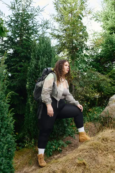 Una donna fiduciosa plus size cammina attraverso una foresta vibrante, godendo della bellezza della natura. — Foto stock