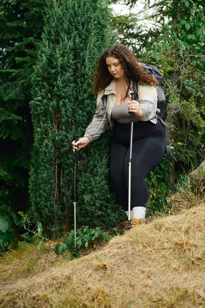 A vibrant plus size woman walks thoughtfully through a lush, green landscape. — Stock Photo