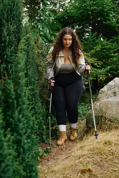 A confident woman in hiking gear strolls through a vibrant forest, exuding joy and grace. — Stock Photo