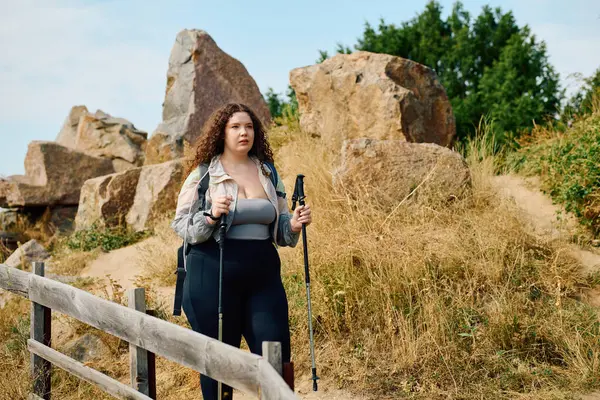 A plus size woman confidently walks through a vibrant field, enjoying the beauty of nature. — Stock Photo