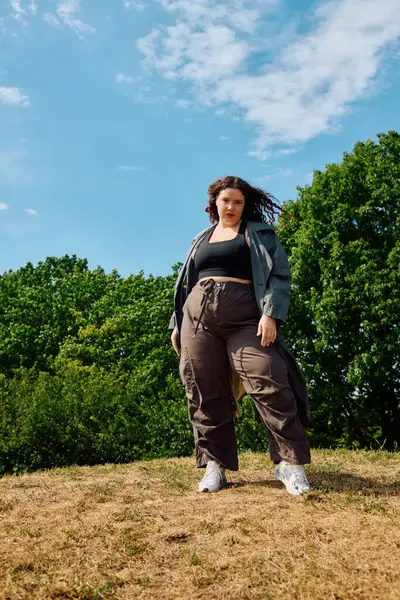 A joyful plus size woman basks in the sun, embracing confidence in a lush green field. — Stock Photo