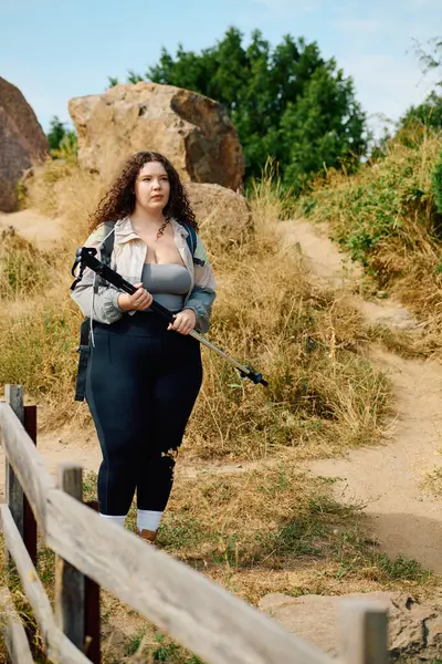 Una gioiosa donna plus size si trova in un campo lussureggiante, abbracciando la bellezza della natura e dell'avventura. — Foto stock