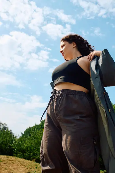 Una mujer de talla grande se levanta con gracia en un campo exuberante, sintiéndose libre en medio de la belleza de la naturaleza. — Stock Photo