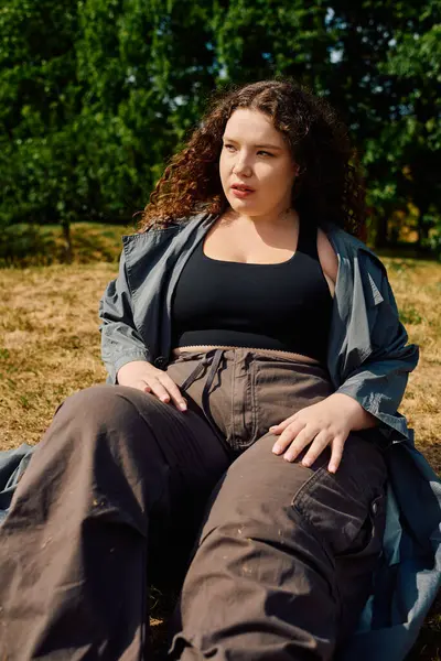 A beautiful plus size woman relaxes in a sunlit field, surrounded by the beauty of nature. — Stock Photo
