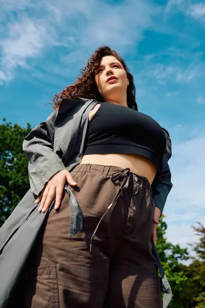 Уверенная женщина plus size гордо стоит в оживленном поле, впитывая красоту природы. — стоковое фото