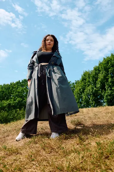 A beautiful plus size woman stands gracefully in a sunlit field surrounded by lush greenery. — Stock Photo