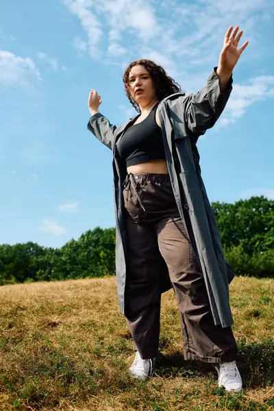 A plus size woman embraces freedom, joyfully dancing in a vibrant, sunlit field under the blue sky. — Stock Photo