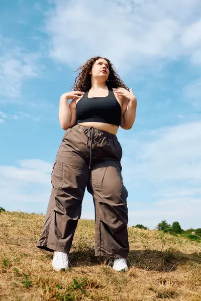 A joyful plus size woman stands in a grassy field, embracing the beauty of nature. — Stock Photo