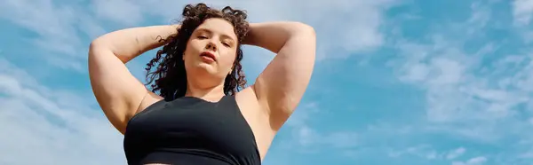 A confident plus size woman stands gracefully in a vibrant field, basking in the sun. — Stock Photo