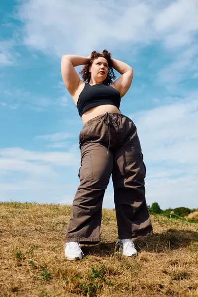 Uma mulher radiante plus size fica alta em um campo dourado, cercada por beleza da natureza e luz. — Fotografia de Stock