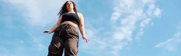 A confident plus size woman embraces natures beauty, standing in a sun drenched field. — Stock Photo