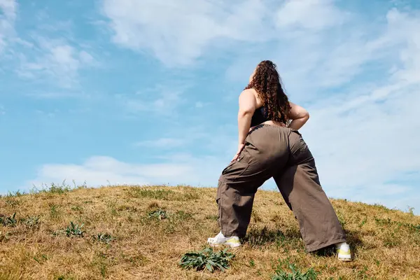 Уверенная в себе женщина plus size стоит на солнечном поле, наслаждаясь красотой природы вокруг себя. — Stock Photo