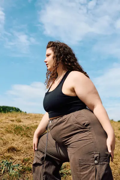 The radiant plus size woman stands gracefully in a lush field, embracing the beauty of nature. — Stock Photo