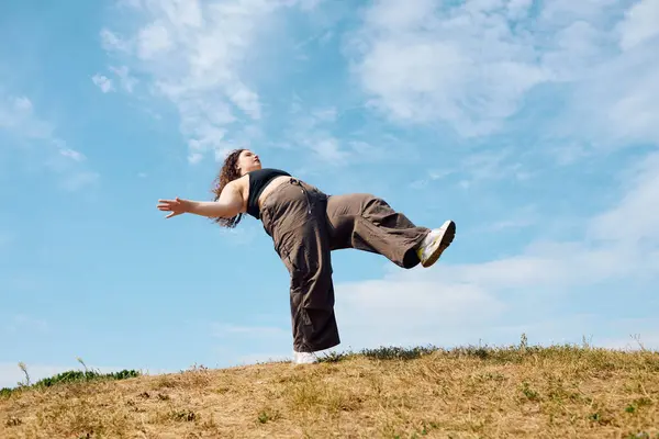A joyful plus size woman enjoys a moment of freedom in a sunny field, dancing gracefully. — Stock Photo