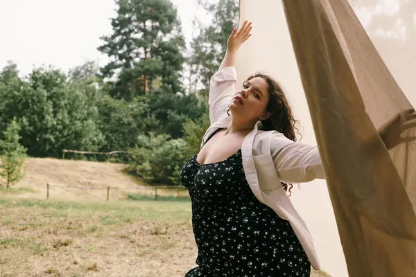 A confident plus size woman embraces nature while dancing in a sunlit field. — Stock Photo