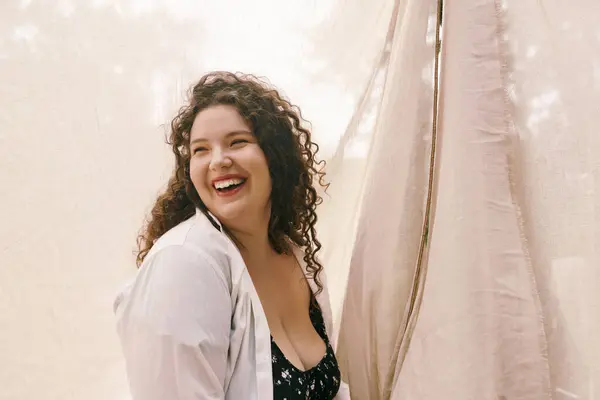 Сияющая женщина plus size, наслаждающаяся мгновением чистой радости в пышном, солнечном поле, заполненном природой. — стоковое фото