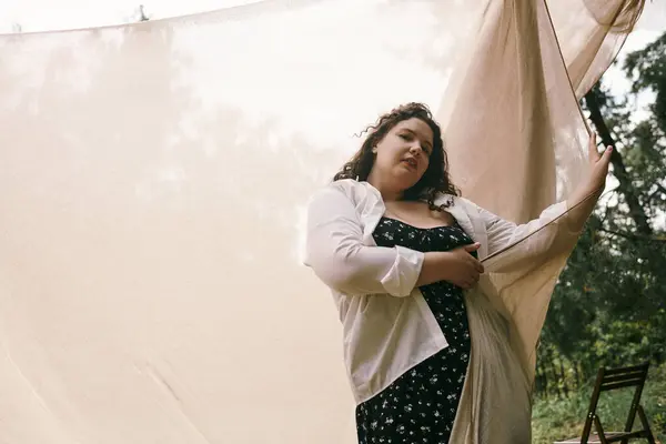 Uma mulher confiante em uma roupa fluindo fica em meio a um campo arejado, irradiando elegância natural. — Fotografia de Stock