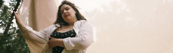 Женщина plus size стоит в оживленном поле, наслаждаясь красотой природы. — стоковое фото