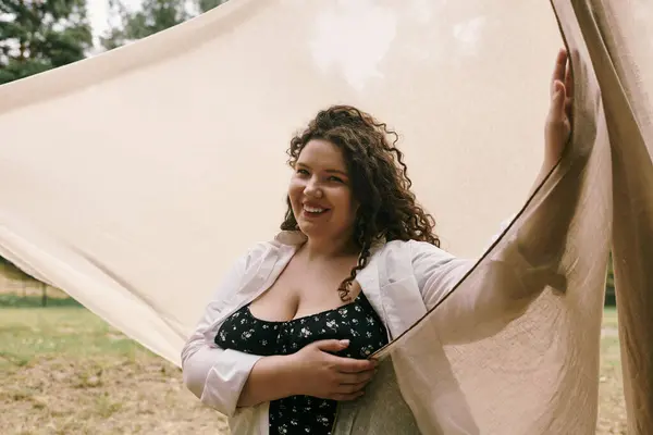 A cheerful plus size woman holds flowing fabric in a field, radiating beauty. — Stock Photo