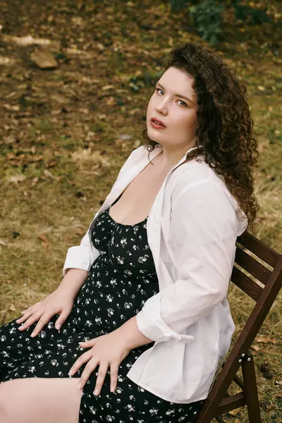 A beautiful plus size woman sits gracefully in a field, surrounded by nature vibrant beauty. — стоковое фото