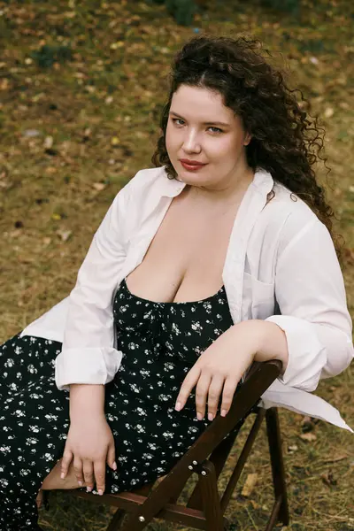 Женщина plus size отдыхает на сереньком поле, наслаждаясь красотой окружающей ее природы. — стоковое фото