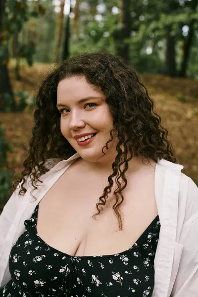 A plus size woman with curly hair smiles warmly, basking in the beauty of a sunny field. — Stock Photo