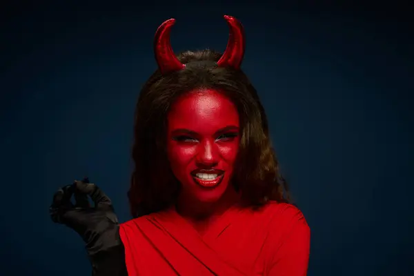 A captivating woman embraces the Halloween spirit in a vibrant red devil costume, smiling playfully. — Stock Photo