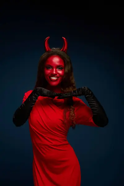 This striking woman in a red devil costume playfully poses, showcasing Halloween spirit. — Stock Photo